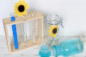 Holz Reagenzglasgestell mit Reagenzgläsern, eins mit Sand, eins mit Sonnenblume, daneben Dekogläser