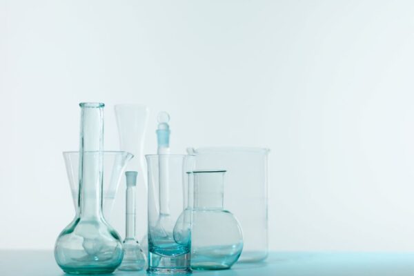 Sur le côté gauche de l'image se trouvent plusieurs verres de laboratoire vides, sur un fond légèrement bleuté.